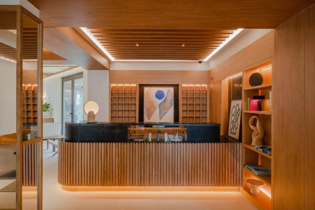 Reception di un hotel boutique con bancone in legno, luci calde e opere d’arte